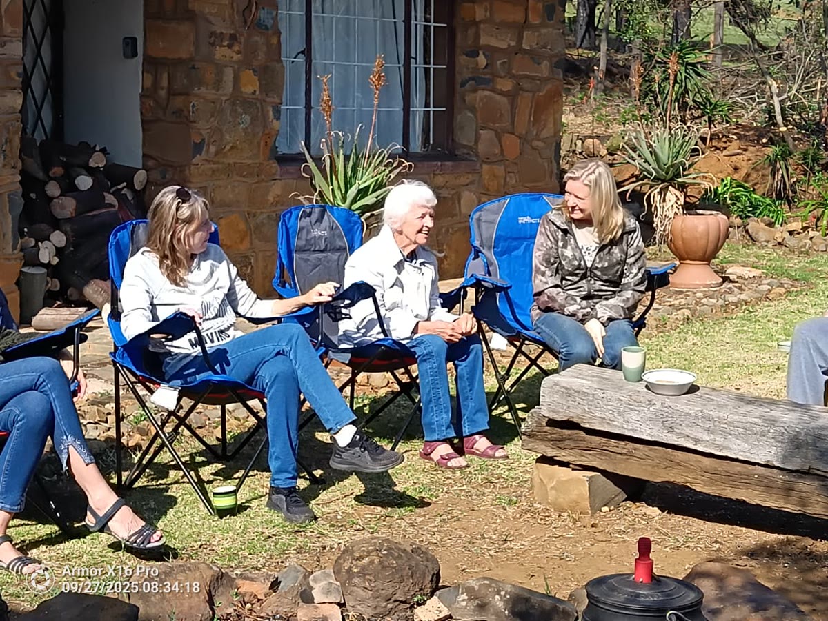 Guests chatting in camp chairs against the stone wall of the house