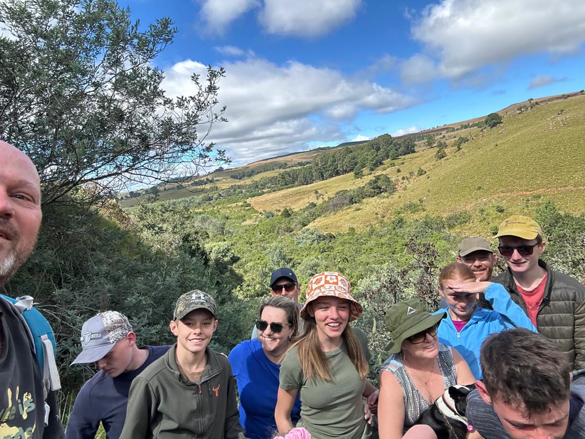 A hiking group smiling on the trail above the valley
