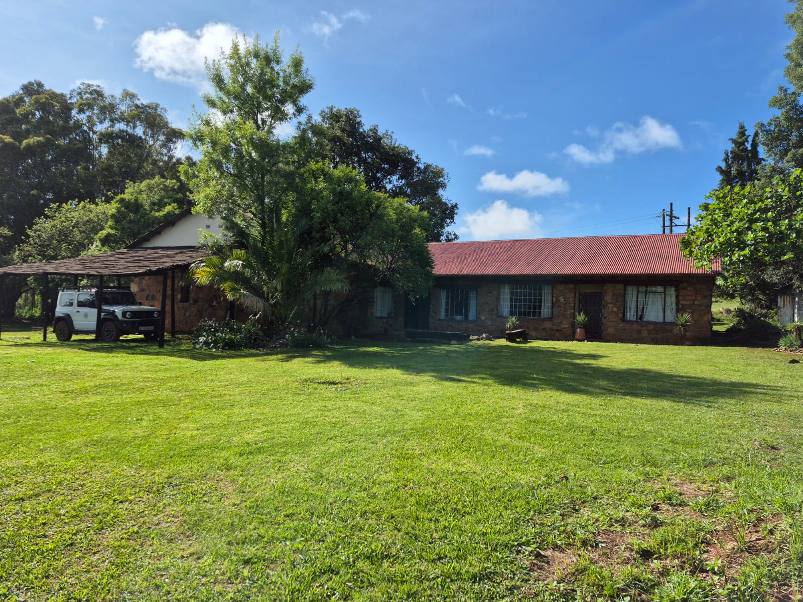 The stone farmhouse with its red roof behind a green lawn