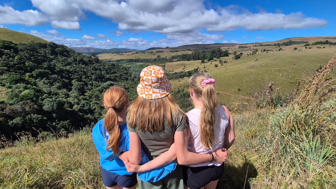 Three girls looking out over the valley from the top of a trail