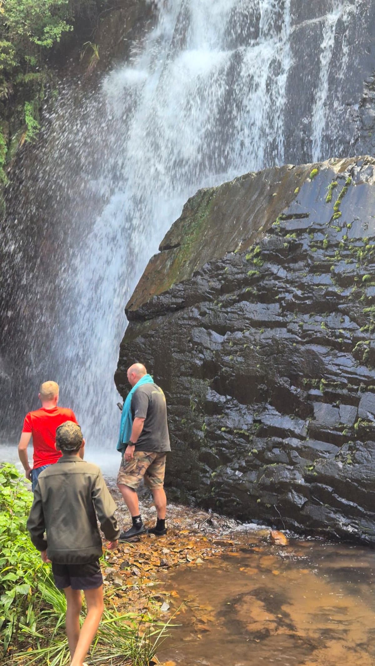 Walkers standing at the base of the waterfall